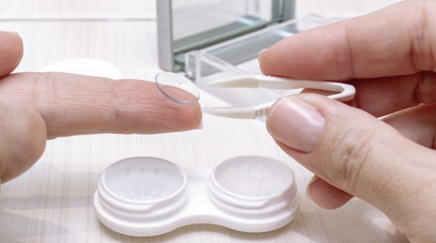 Cropped female hands taking contact lenses out of a container.